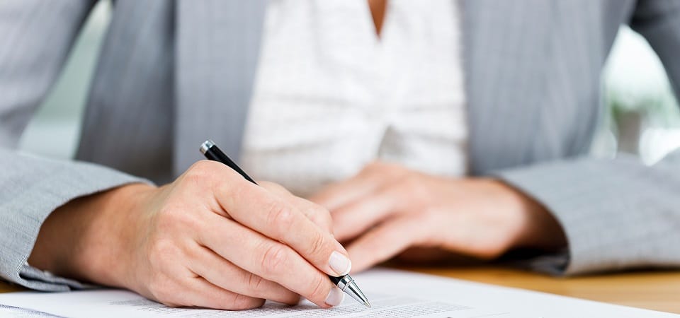 Close-up shot of businesswoman filling out insurance policy in h